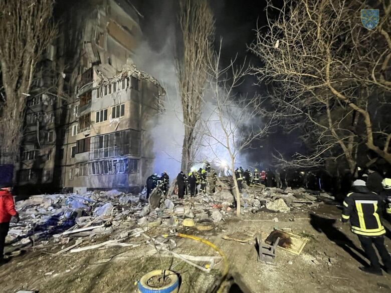 A heavily damaged apartment building with rising smoke