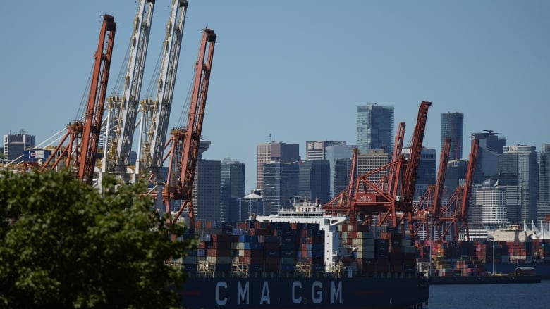 Cranes and shipping containers near a port on a hazy day.