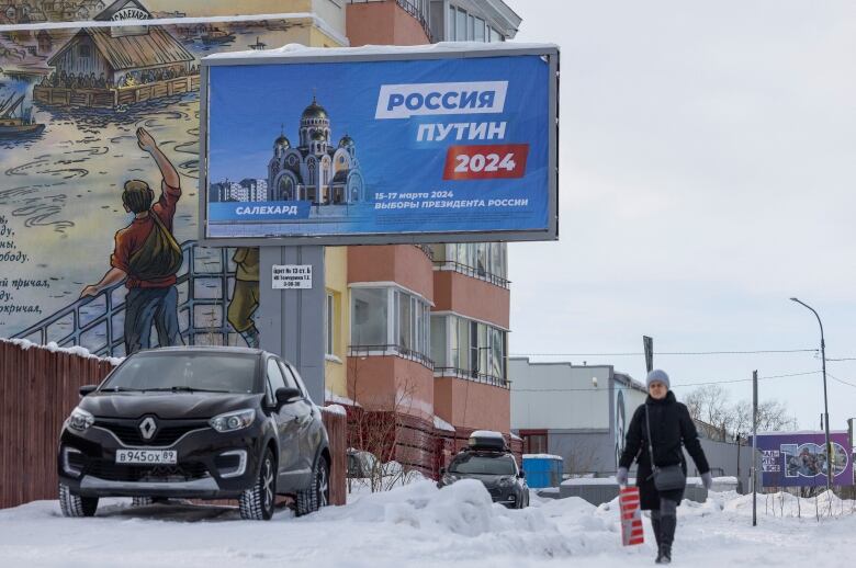 A woman walks past a campaign banner in support of Vladimir Putin, Russian incumbent President and a candidate in the March 2024 presidential election in Salekhard, in the Yamal-Nenets Region, Russia February 22, 2024. 