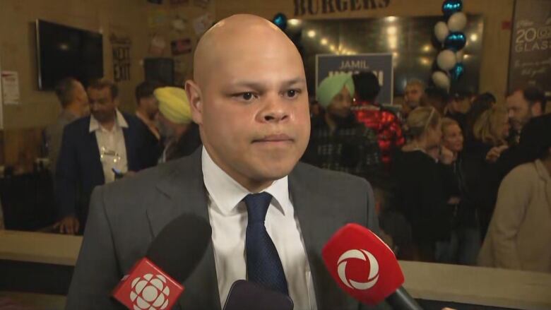 A man in a suit speaks to reporters.