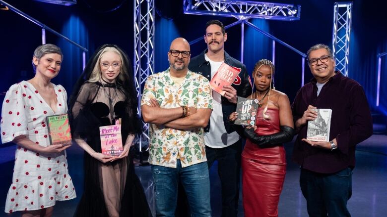 A portrait of the cast of Canada Reads 2024 holding their respective books in the television studio.