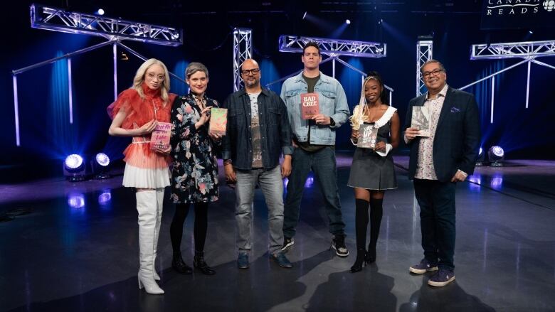 A portrait of the cast of Canada Reads 2024 holding their respective books in the television studio.