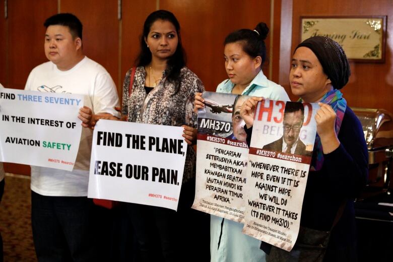 People hold signs asking authorities to find the missing plane. 