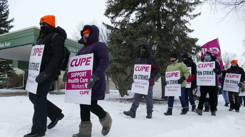 A group of people carrying signs are pictured.