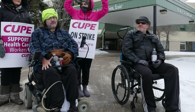 Two men sitting in wheelchairs are pictured outside.