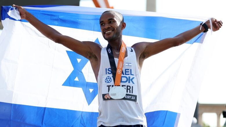 A male athlete celebrates with the Israel flag.