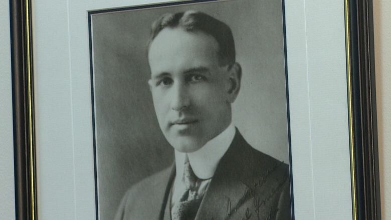 A black and white photo of a young man is displayed in a frame. 