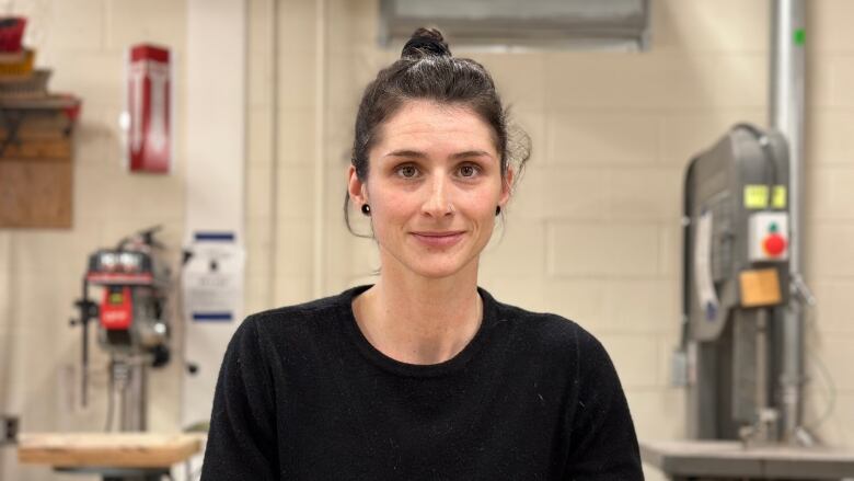 A woman stands in a workshop.