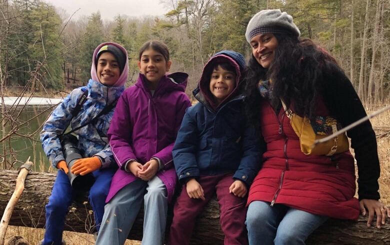 happy family sits on a log surrounded by a forest