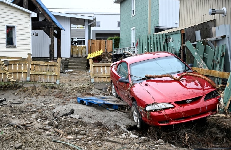 A car sits in the backyard of a house after a major spring flood hit the region on Wednesday, May 3, 2023 in Baie-Saint-Paul Que.