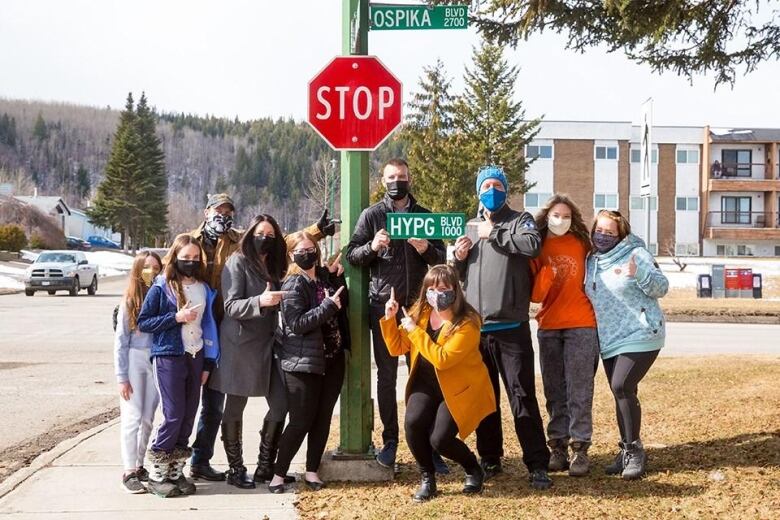 People standing with a street sign that says 'HYPG Blvd.'