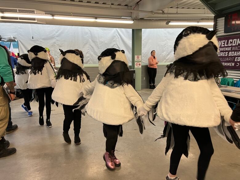 people in bird costumes run in a line