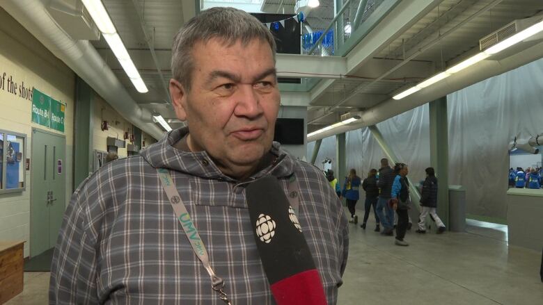 A man with a CBC microphone pointed at him looks off to the side of the camera 