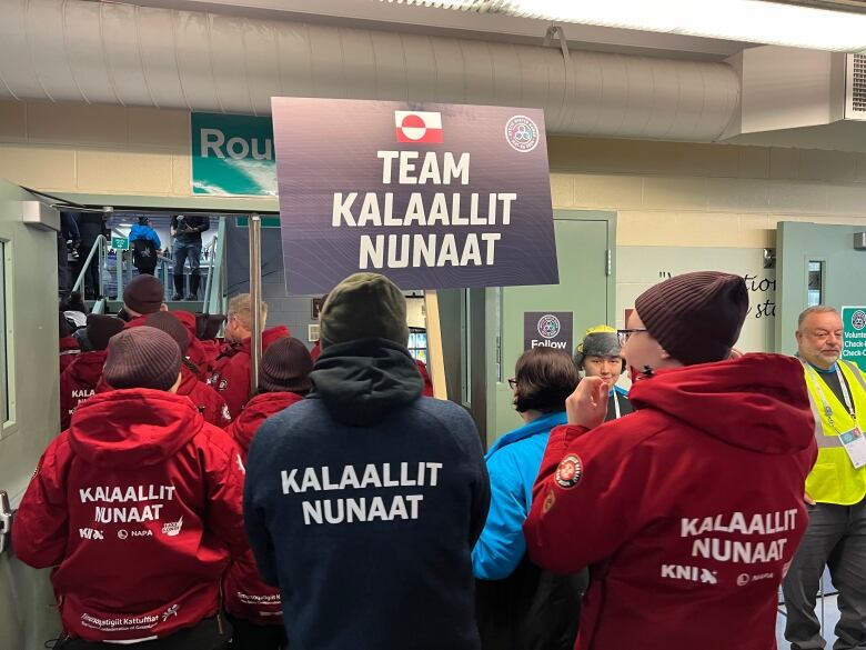 People seen from the back hold signs that read 'Kallaallit Nunaat.'