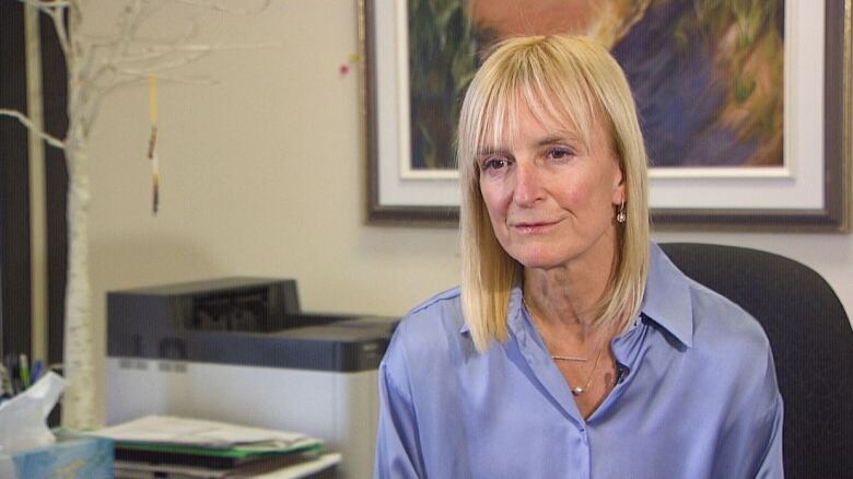 Woman with blond hair sitting in office.