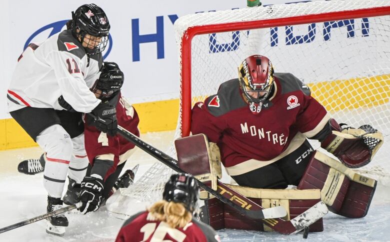 A hockey player tries an in-close shot against a goaltender.