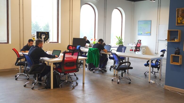 Four people work across two shared desks in a co-working space.