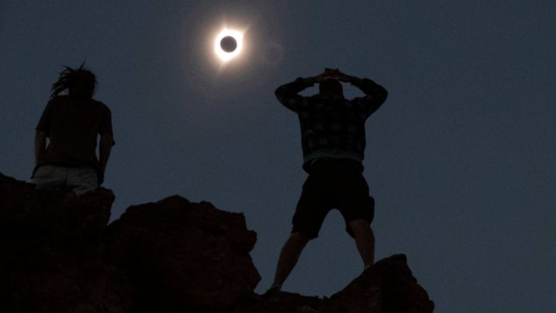 People stand in darkness during a total solar eclipse.