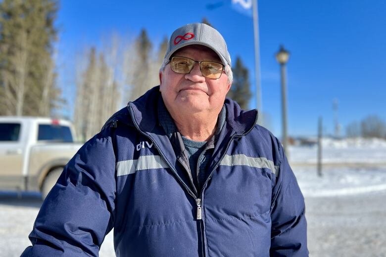 A man stands outside on a sunny winter's day.