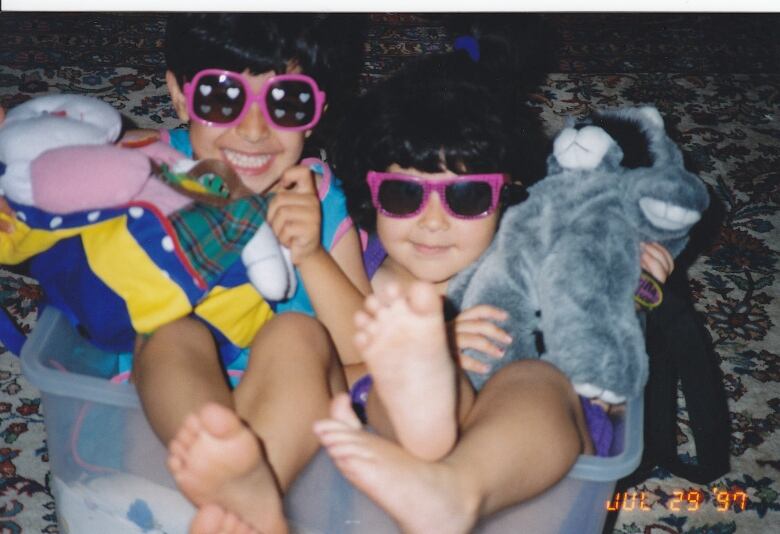 Two young girls in sunglasses pose in this old photo.