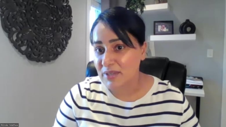 A South Asian woman with short hair speaks while seated at a computer.