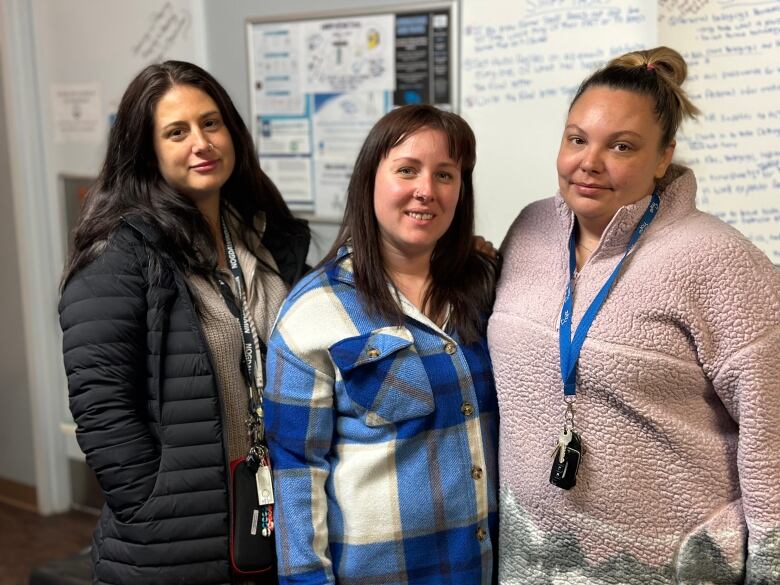 Three women standing in an office.