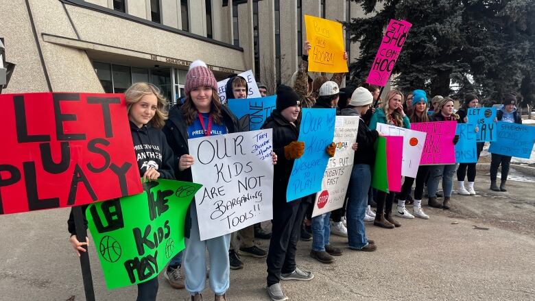 Students hold signs including ones that say 