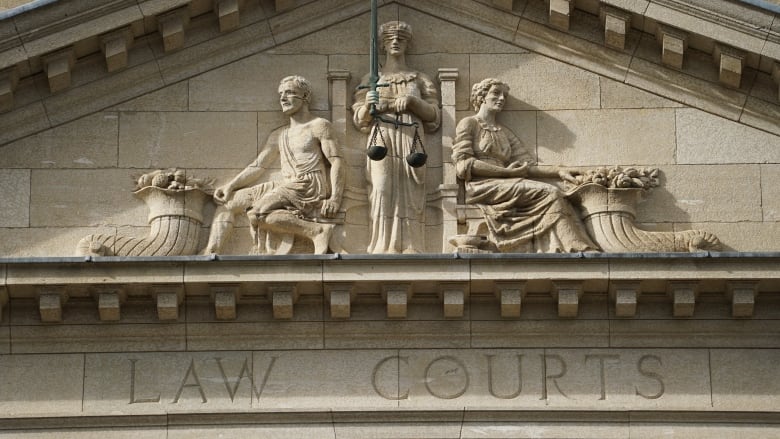 A frieze depicts two figures on either side of a blindfolded woman holding scales. Under the frieze are the words 