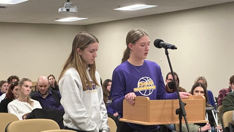 Two teens stand at a podium