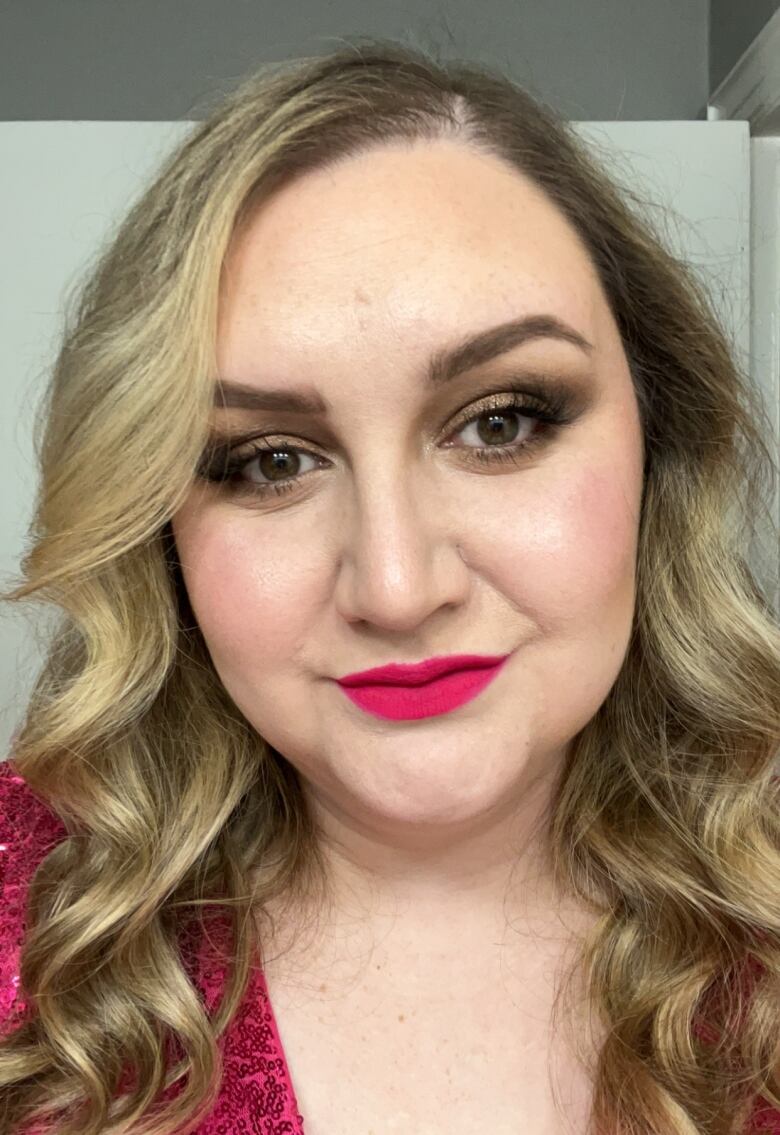 Woman with blond curls and pink lipstick staring into screen