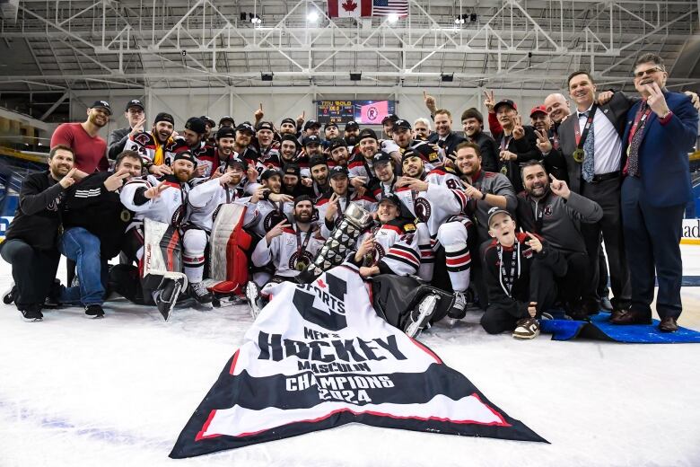 A hockey team poses with a championship banner 