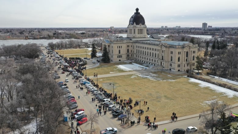 A photo taken by a drone high in the sky shows a legislative building with people walking in front of it.