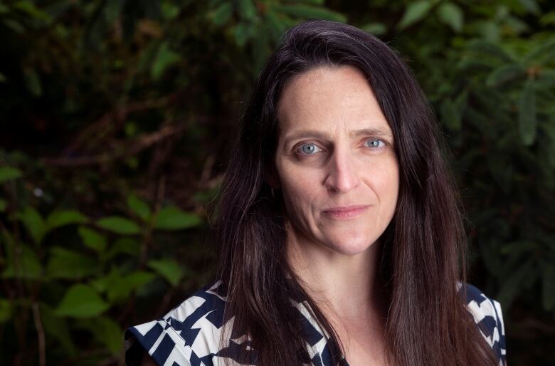 A woman with long brown hair is wearing a patterned black and white top.