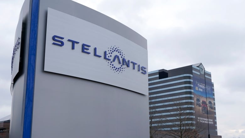 A large blue logo reading Stellantis is affixed to a building.