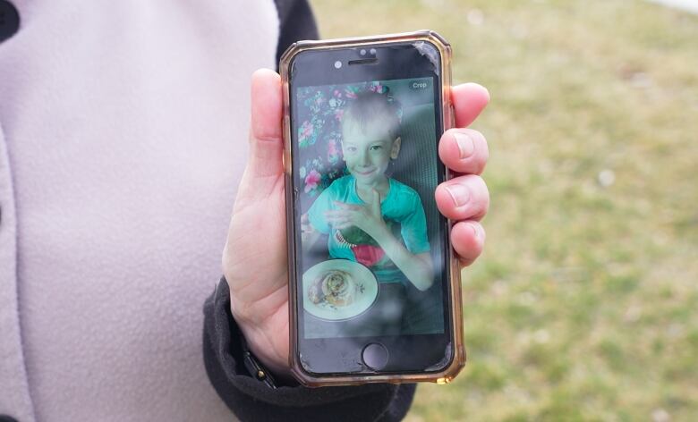 Debi Hart holds a photo of her grandson Sawyer, who is pictured in 2021 when he was first diagnosed with Chron's disease. 