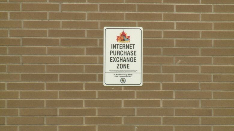 A sign on a brick wall overlooking a parking lot.