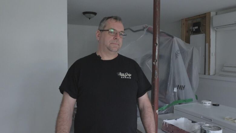 a man stands in a basement that is undergoing repairs after flooding. 