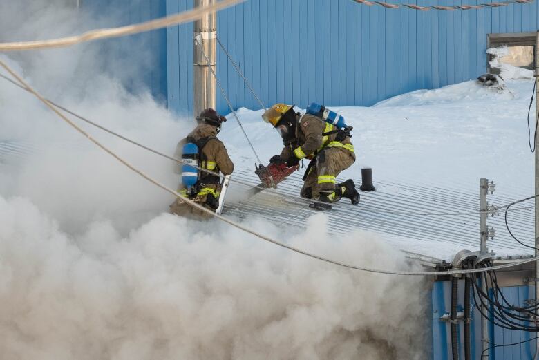 Two firefighters with smoke billowing around them 