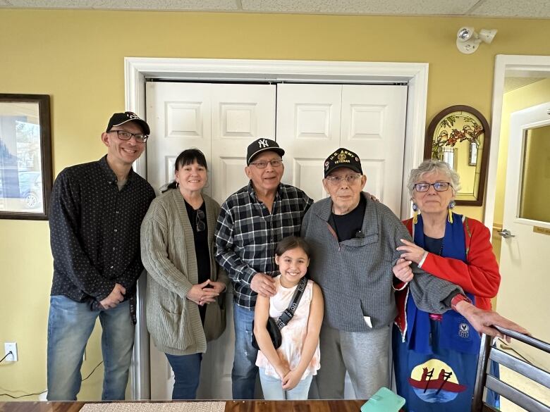 Five adults and a young girl stand together for a group photo.