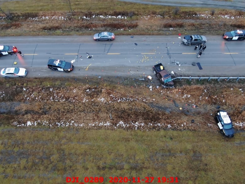 Aerial photograph showing a crashed car in a road, surrounding by several police cars and a few standing police men. 