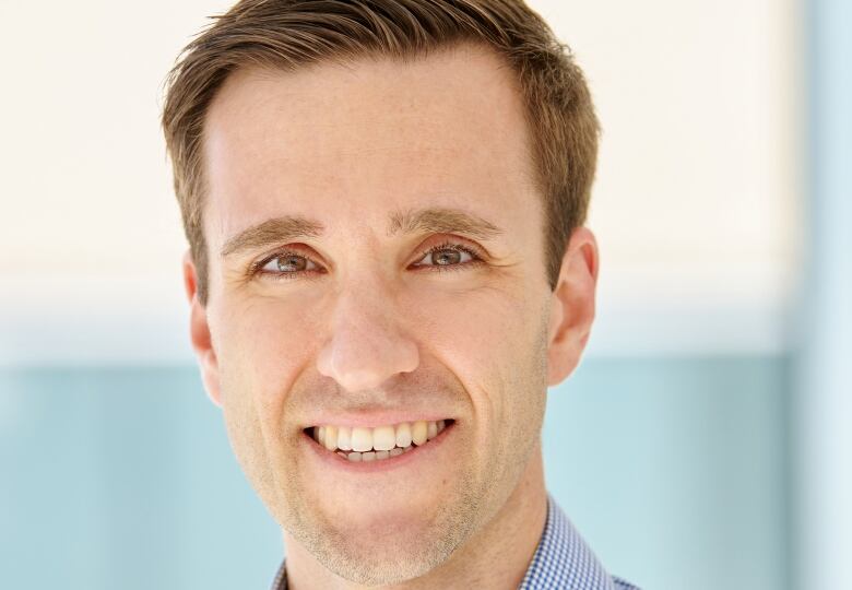 A man in a blue shirt smiles at the camera. 