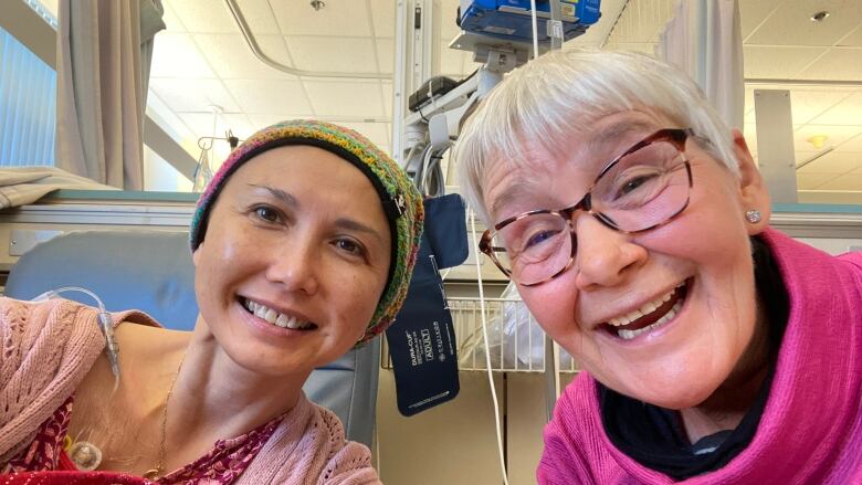 Two women smile widely in a hospital room. 