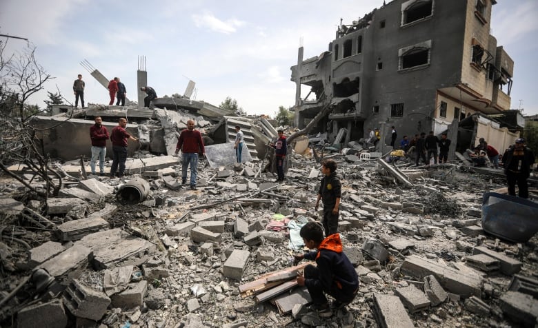 People look through the rubble of demolished buildings.