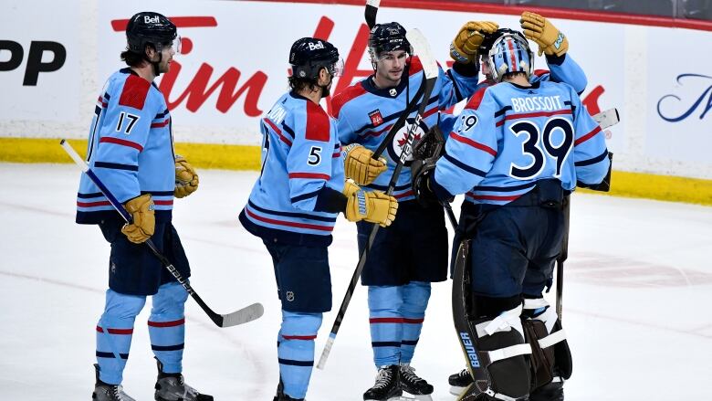 A group of hockey players celebrate their win on the ice.