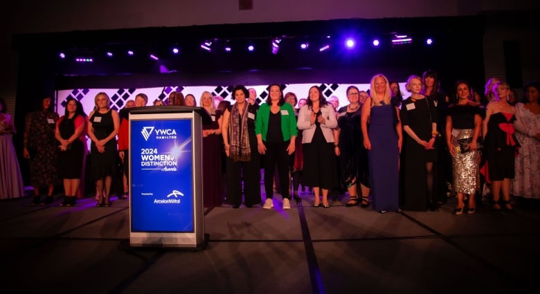 Women stand on stage.