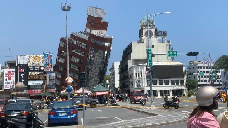 A mulistorey building is shown toppled over from a distance in an urban setting.