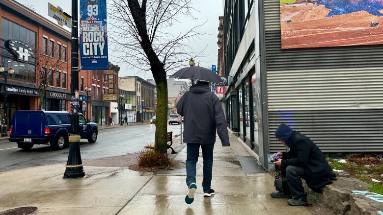 man walks down street with umbrella