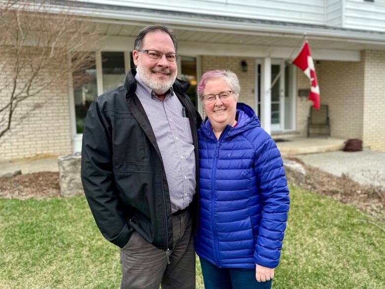 man and woman stand outside house