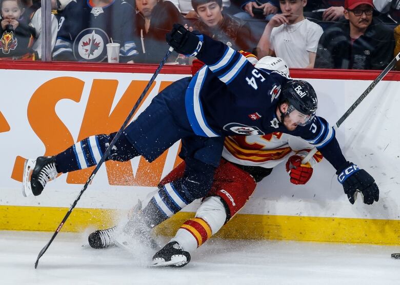 Two hockey players collide along the boards.