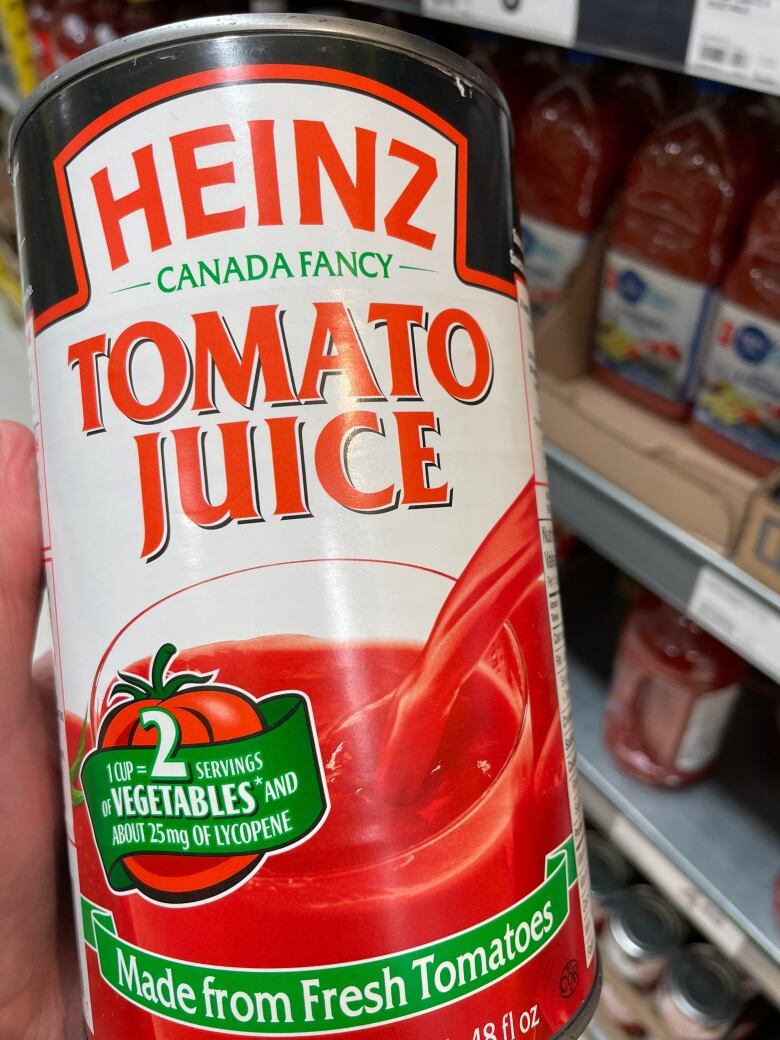 A hand holds a ribbed metal can with red and white lettering.